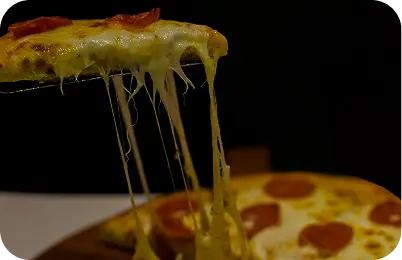 Slice of pizza with melted cheese being lifted from the plate