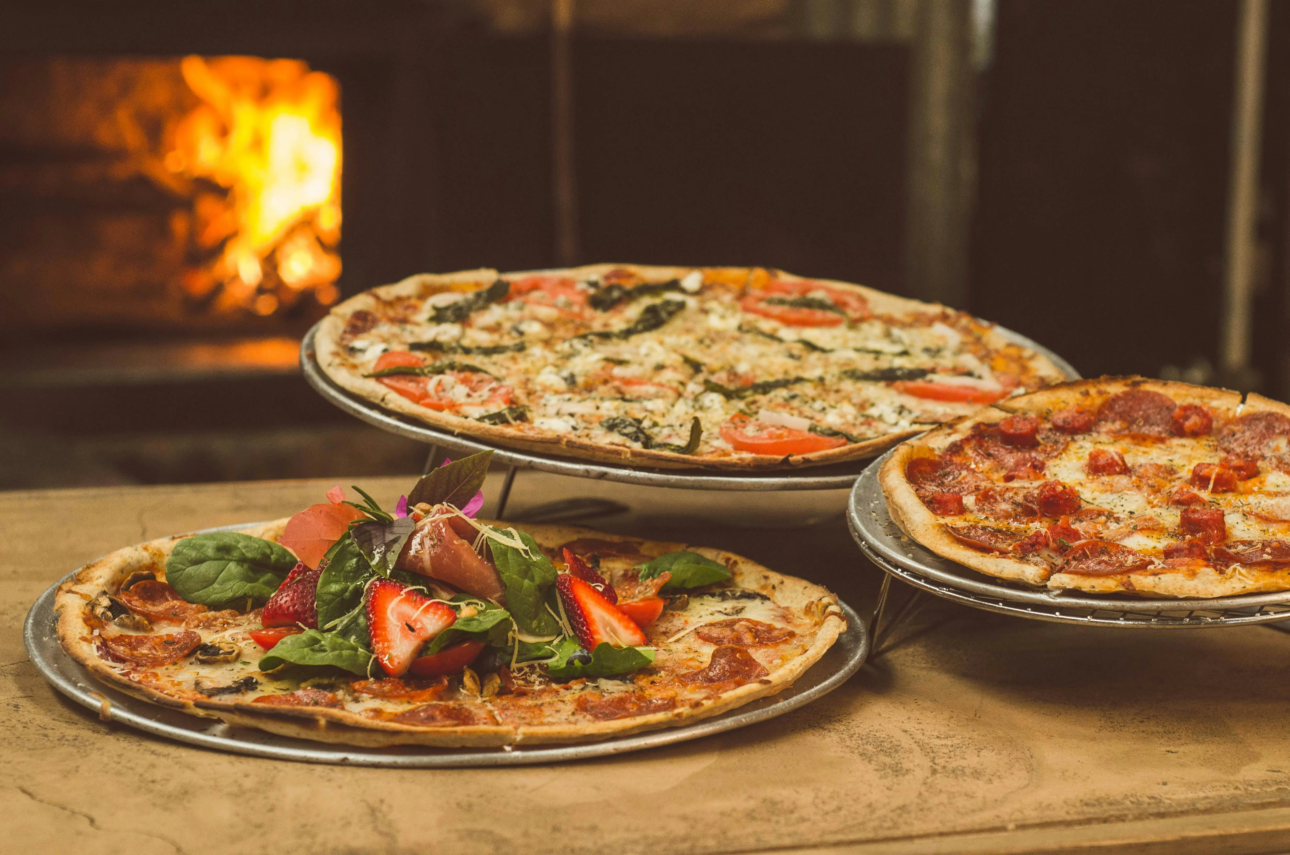 Three wood-fired pizzas with different toppings